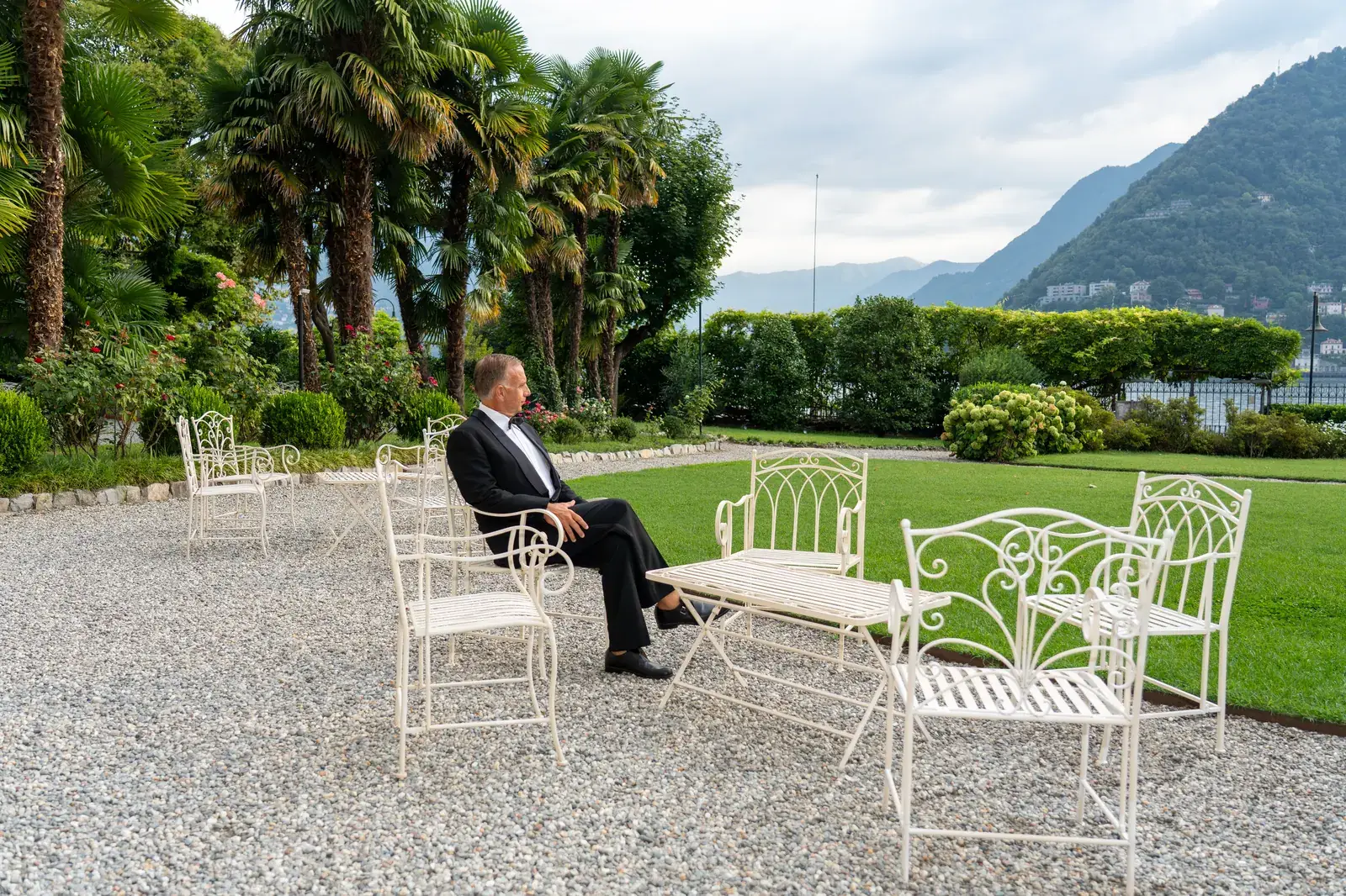 White wrought-iron garden furniture on the gravel terrace, palms and Lake Como behind